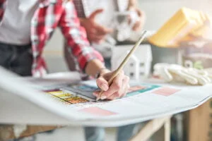 Cropped photo of a draftswoman and her colleague working at an architectural drawing at the table
